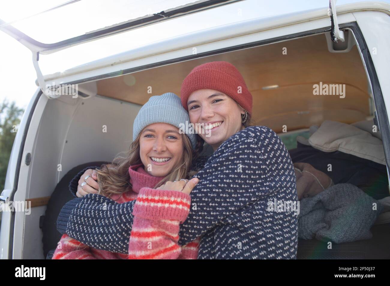 Portrait happy young women friends hugging outside camper van Stock Photo