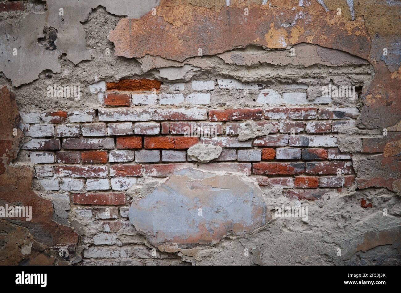 Brick wall with pieces of plaster. Wall of an old building in need of renovation. Aged wall texture of  brick building close up. Grunge background Stock Photo