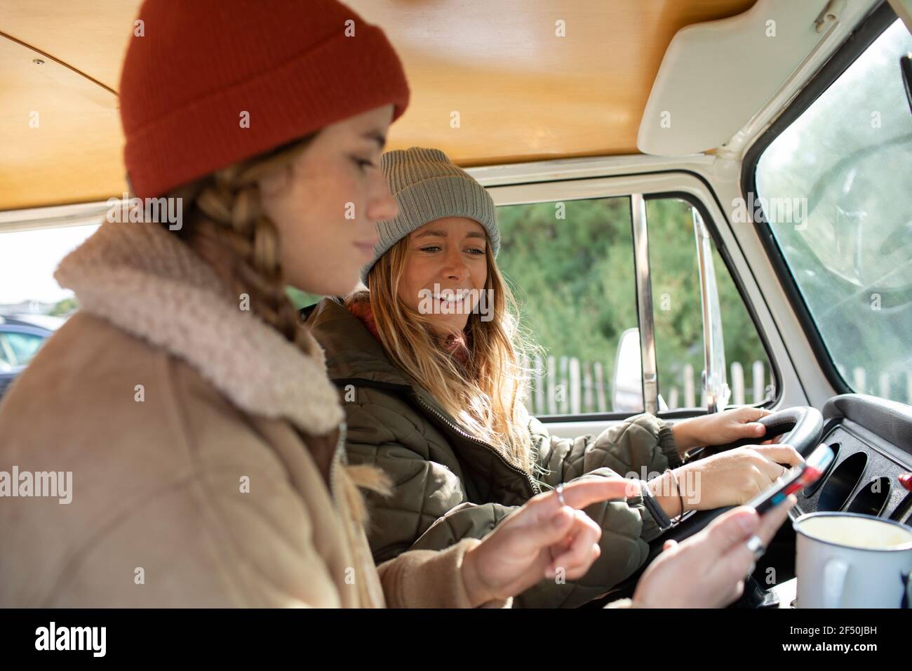 Young women friends using smart phone in van Stock Photo