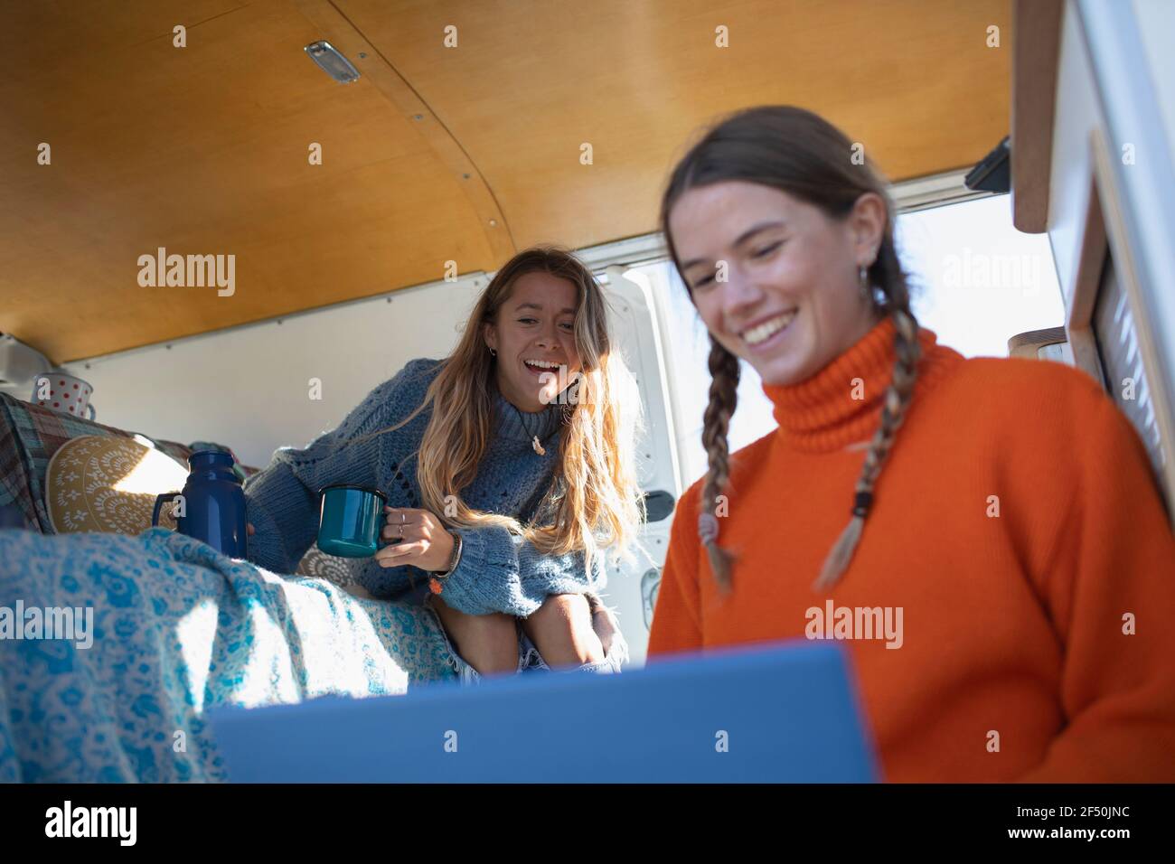Happy young women friends using laptop in camper van Stock Photo