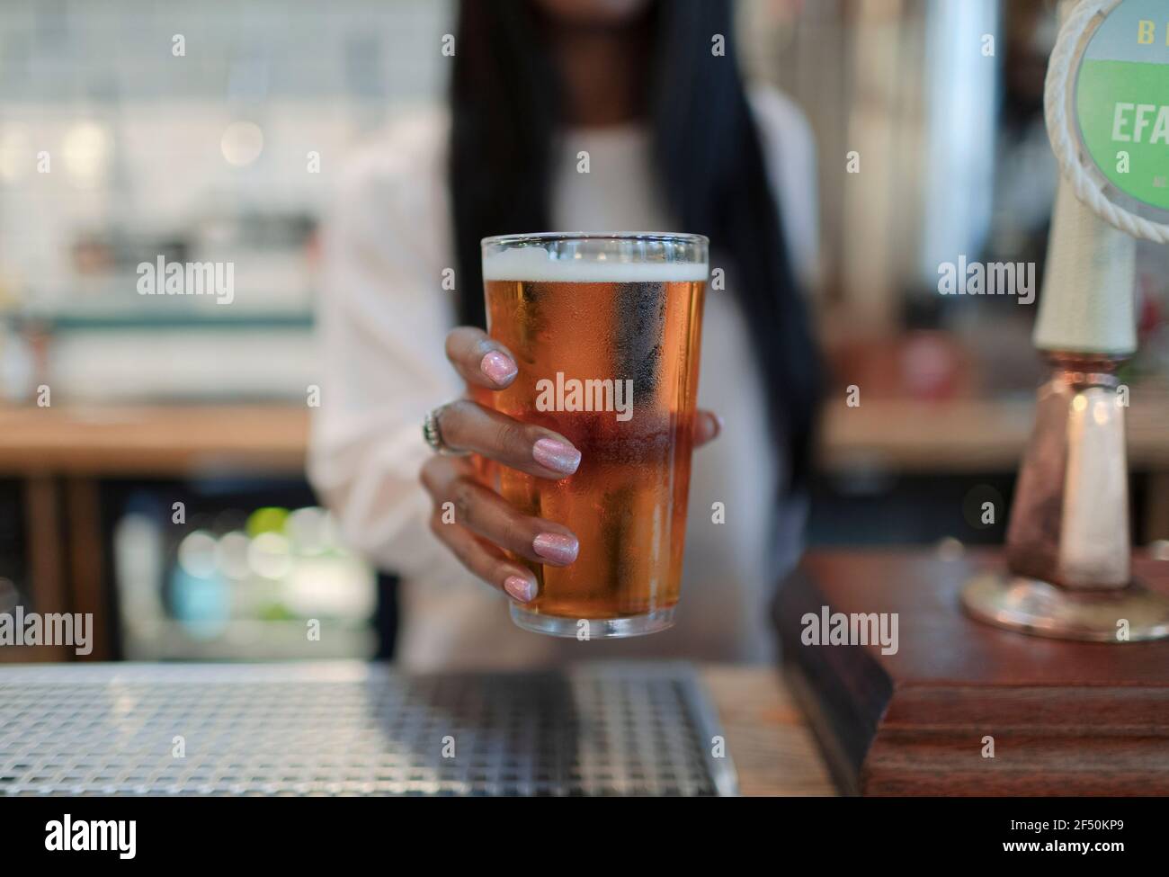Close up female bartender serving pint of beer in pub Stock Photo