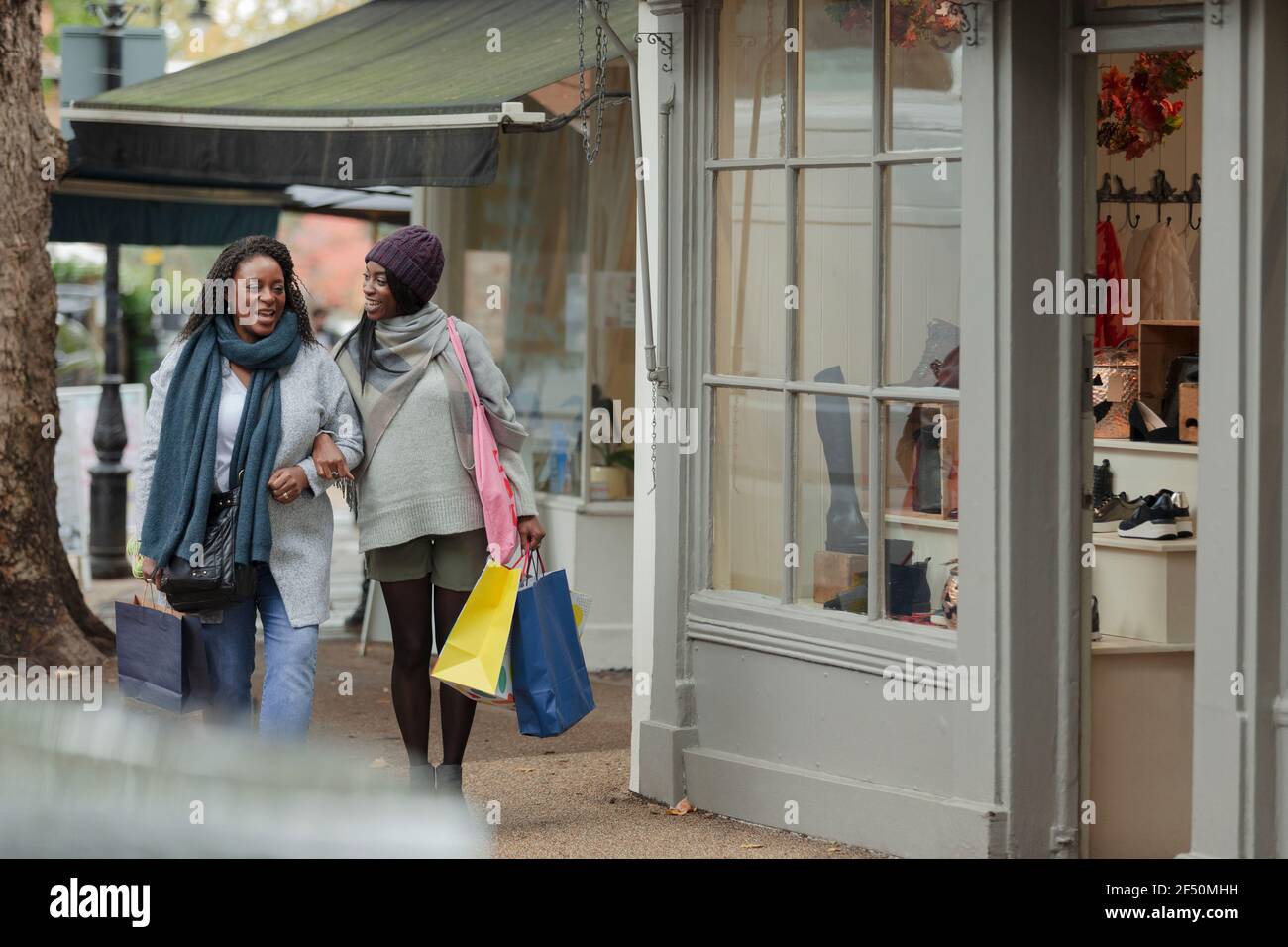 Happy mother and daughter walking arm in arm with shopping bags Stock Photo
