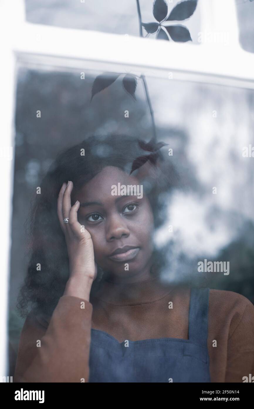 Sad young woman with head in hands looking out window Stock Photo