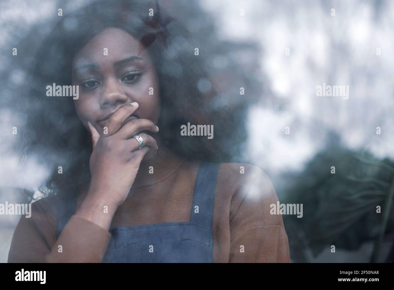 Sad woman with hand on chin at window Stock Photo