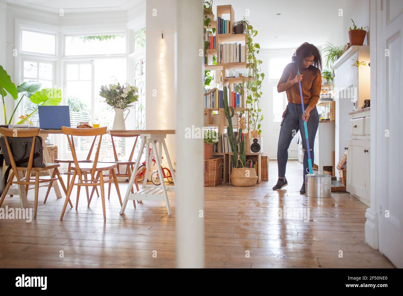 Woman mopping hardwood kitchen floor in apartment Stock Photo