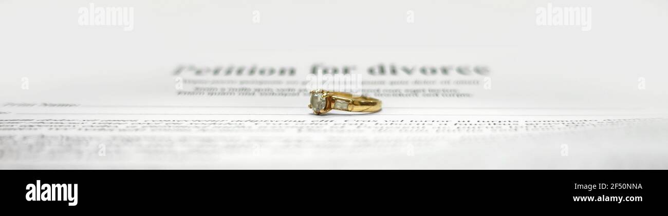 Conceptual image for divorce with two golden wedding rings in the middle and petition for divorce as background. Main focus on the rings. Stock Photo