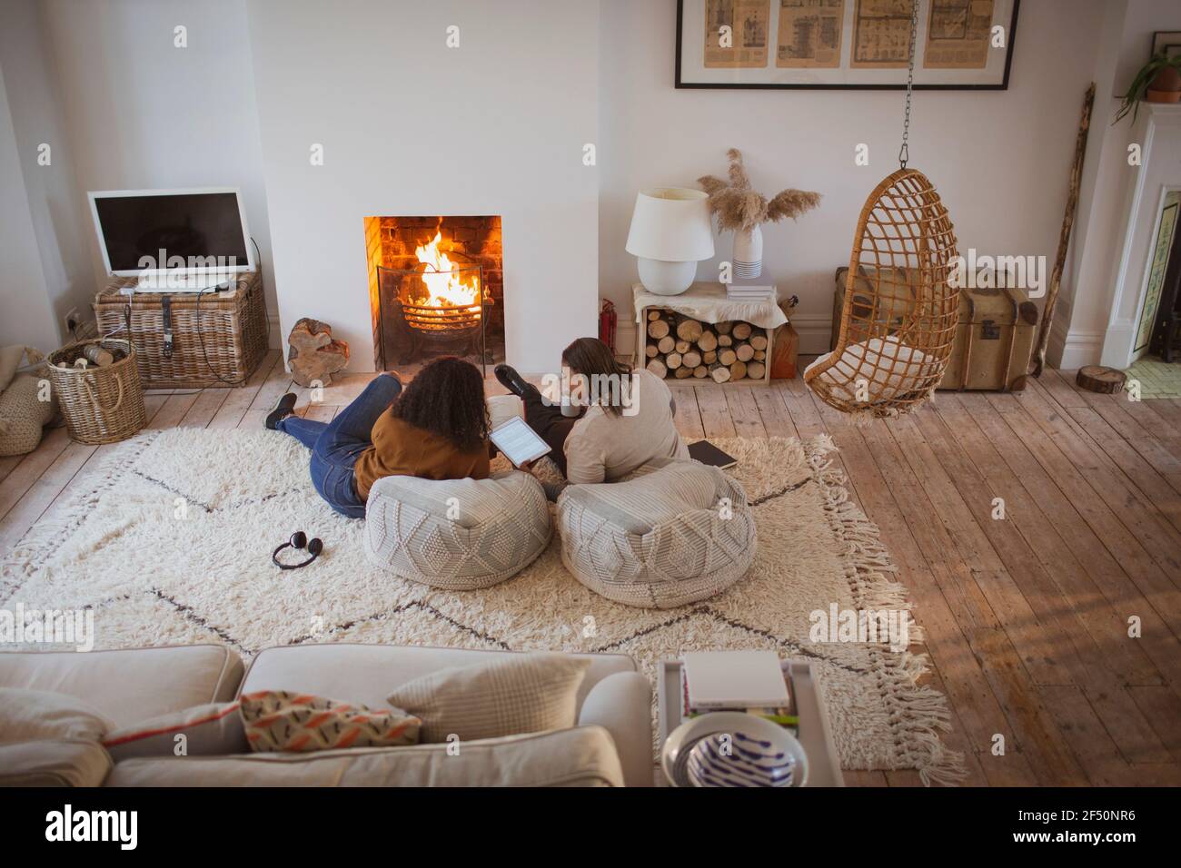 Mother and daughter relaxing with digital tablet by cozy fireplace Stock Photo