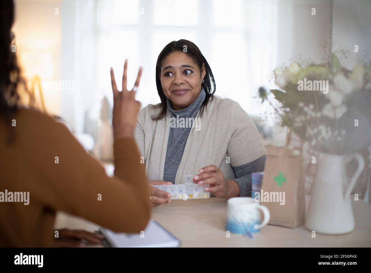 Daughter helping mother with pill box take prescription medication Stock Photo