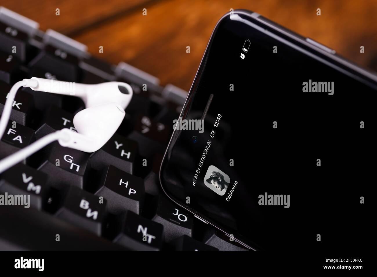 MINSK, BELARUS - MARCH 22, 2021: View the Clubhouse app on a smartphone. Clubhouse is an audio chat app. Smartphone and headphones on the keyboard. Stock Photo