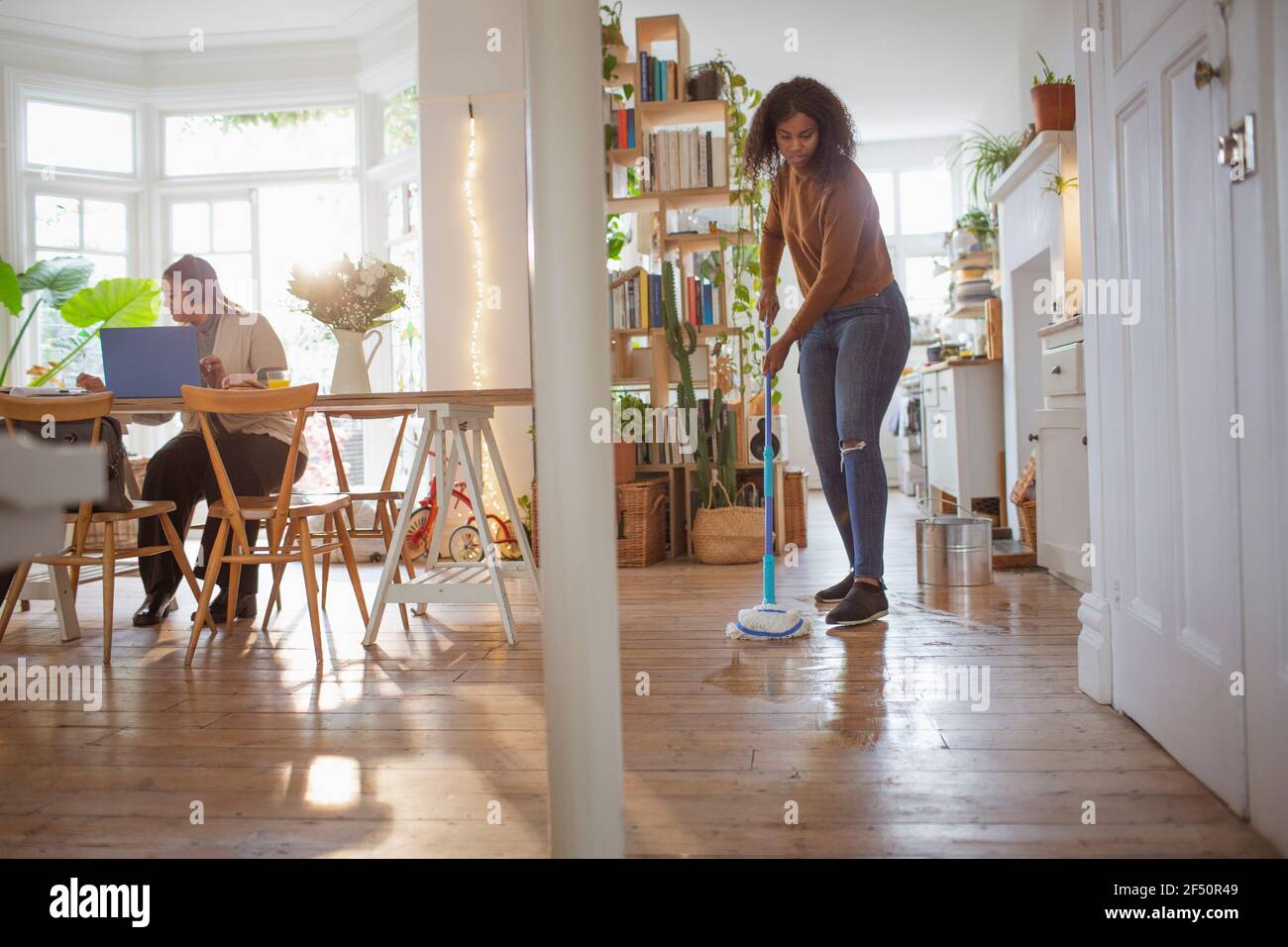 Women working and mopping hardwood floor in apartment Stock Photo