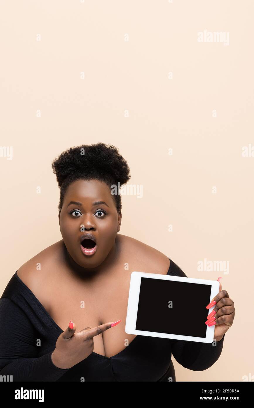 shocked african american plus size woman holding digital tablet with ...