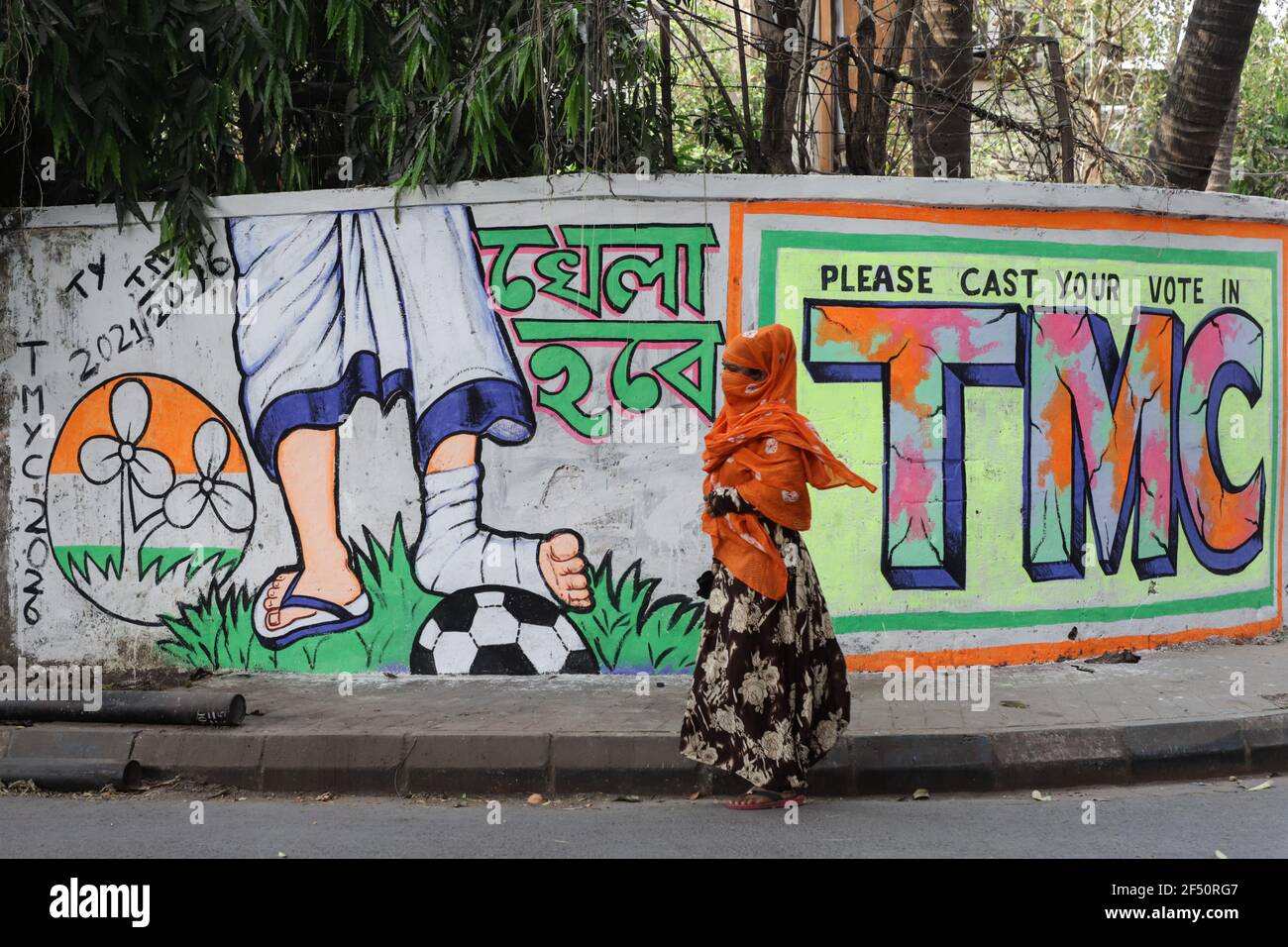 A muslim woman walks past a satirical political wall made by TMC (Trinamool Congress Party) prior to the assembly polls of West Bengal.Members of different political parties of West Bengal painted the walls of the streets in Kolkata with political symbols and cartoons prior to the assembly elections. Stock Photo