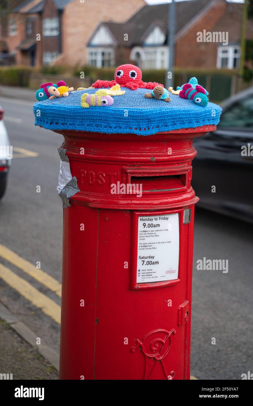 Red, postbox, post box, crocheted, Royal Mail, woolly hats, covers, hand-knitted, pillar boxes, Lincoln City, Sea creatures, Easter Rabbits, flowers. Stock Photo