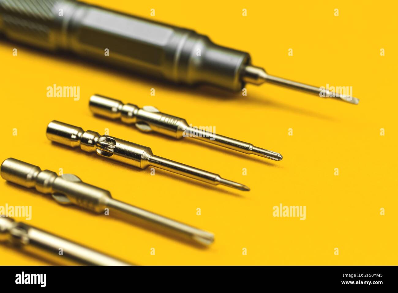 Screwdriver with replaceable metal bits on yellow background Stock Photo