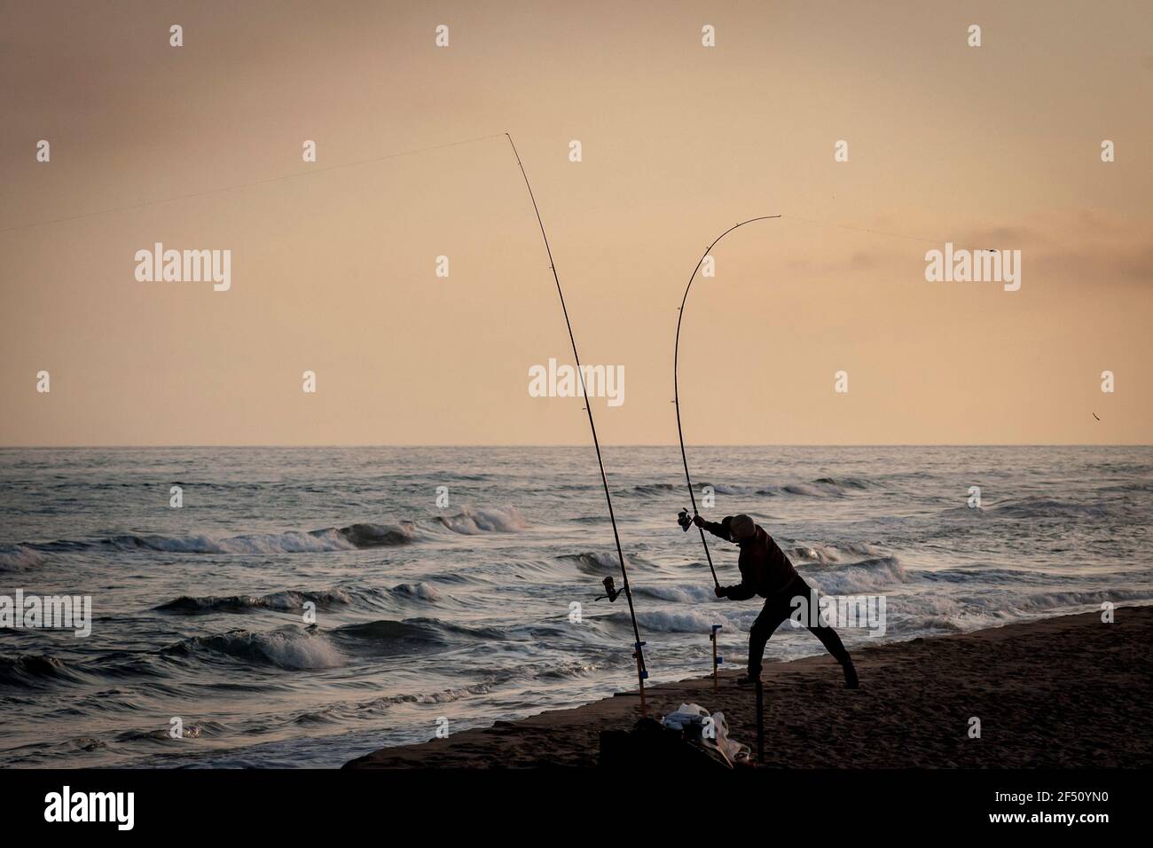 A man throws his fishing rod at el Prat de Llobregat beach, Barcelona. Stock Photo
