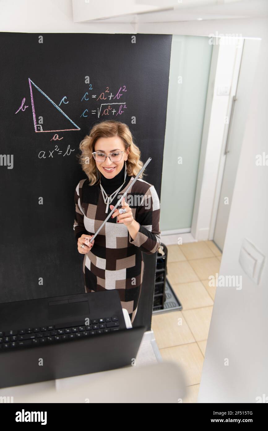 Young female math teacher explaining geometry on the black wall Stock Photo