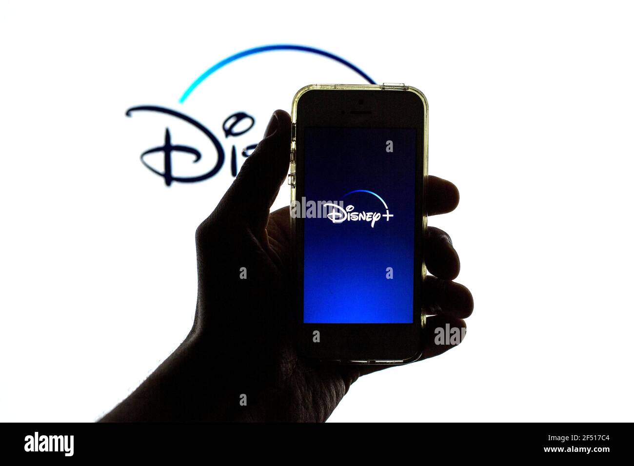 In this photo illustration the Disney+ App seen displayed on a smartphone screen and a Disney+ logo in the background Stock Photo