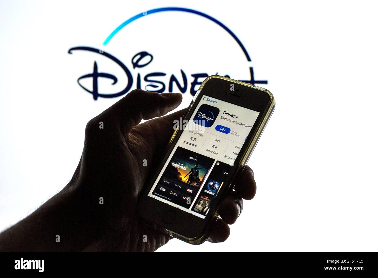 In this photo illustration the Disney+ App in App Store seen displayed on a smartphone screen and a Disney+ logo in the background Stock Photo