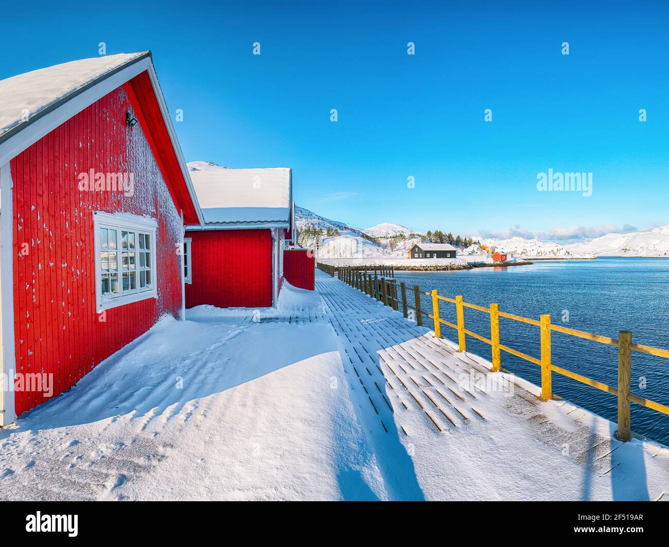 Traditional Norwegian red wooden houses on the shore of  Sundstraumen strait  that separates Moskenesoya and Flakstadoya islands. Location: Flakstadoy Stock Photo