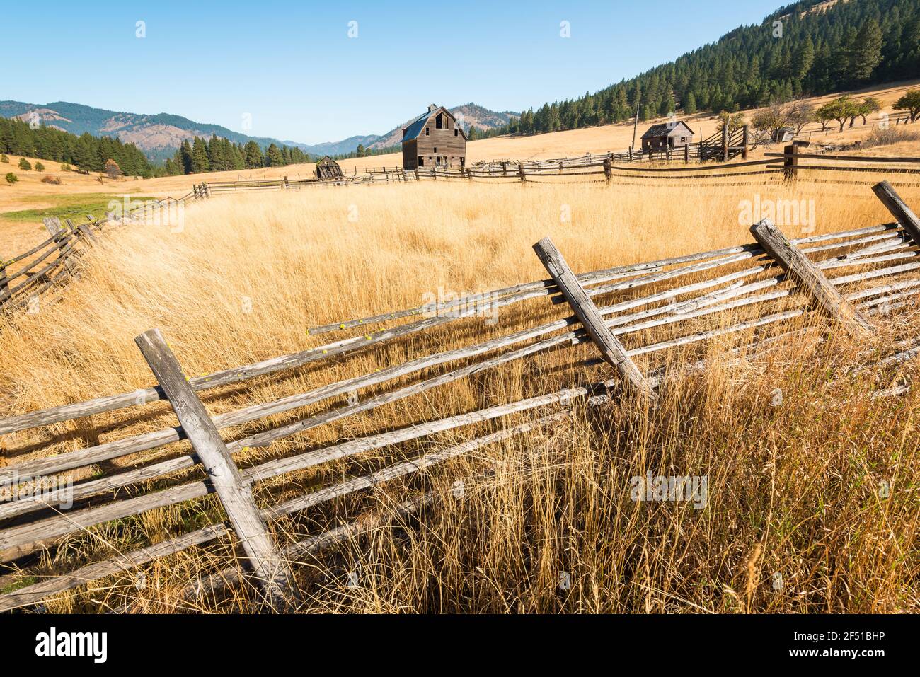 Late Fall scene in rural Eastern Washington State with broken fence falling over and an old barn near Cle Elum and the Cascade Mountains Stock Photo