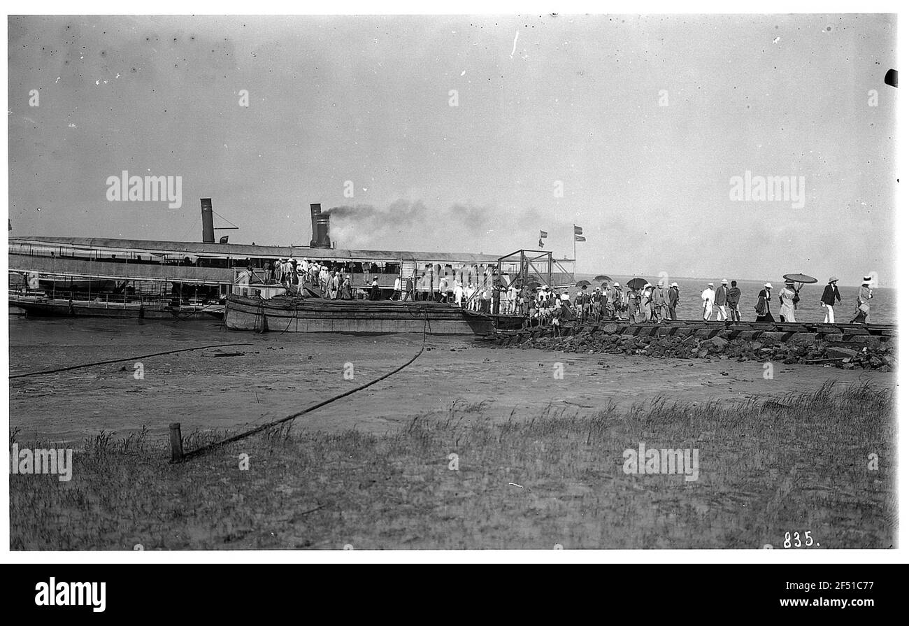 Diamond Harbor (India). Jetty with landing bridge and there moored steaming boats. Passengers at the district and local luggage rack Stock Photo