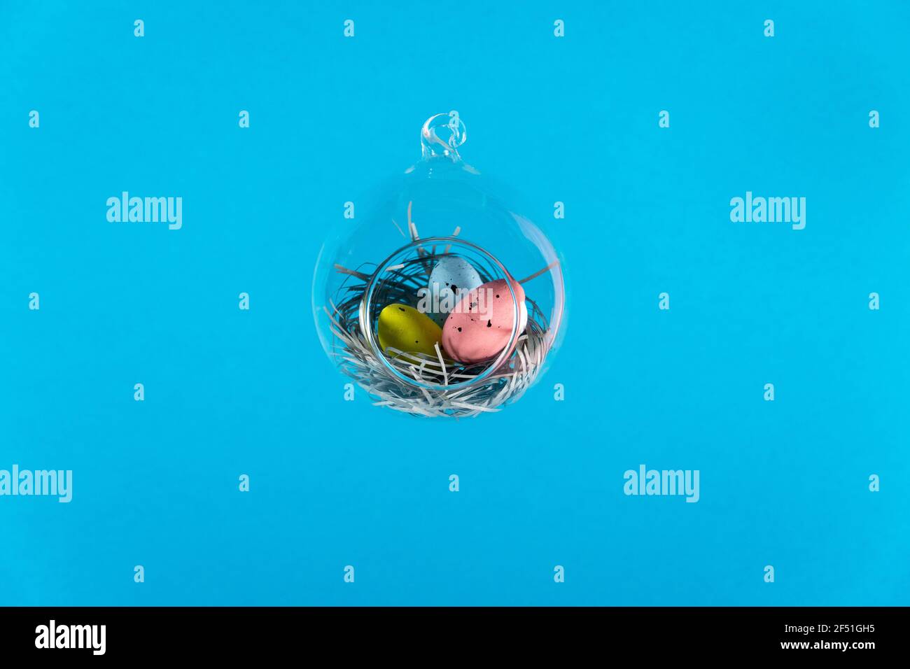 Three eggs in a floating glass nest. Blue background. Creative Easter concept Stock Photo