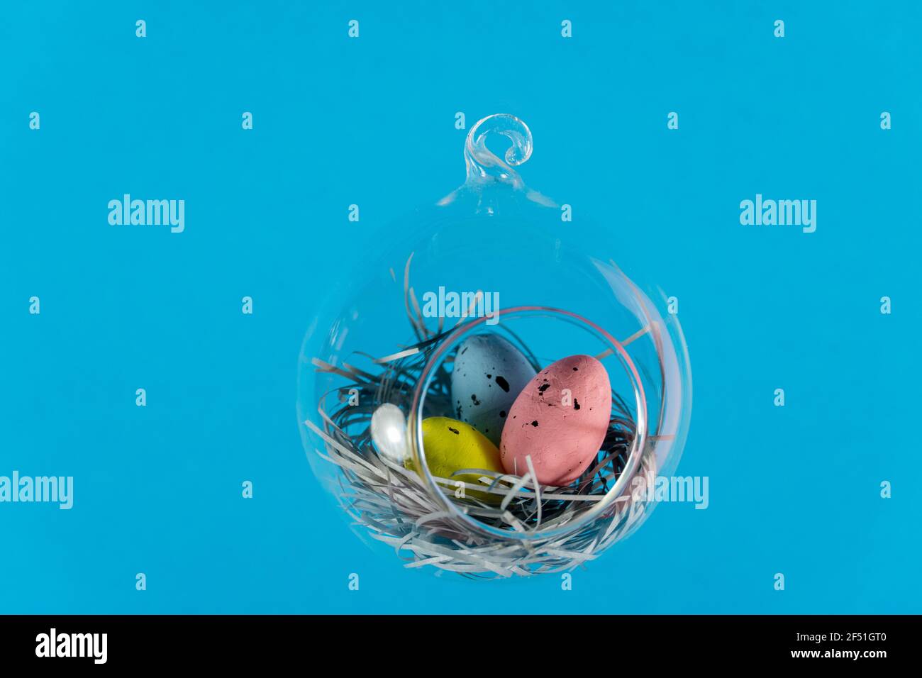 Three eggs in a floating glass nest. Blue background. Creative Easter concept Stock Photo