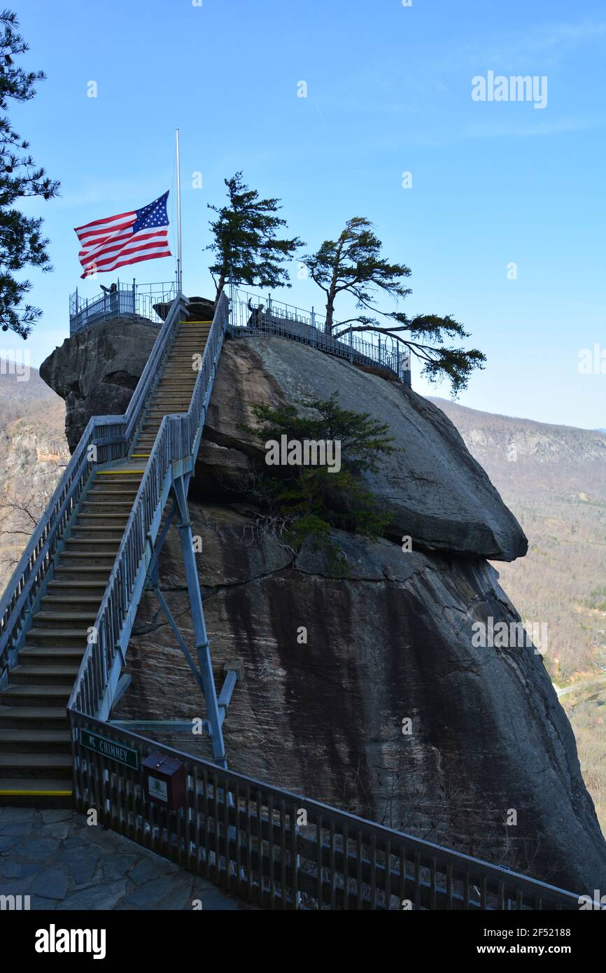 The American flag blows atop the namesake granite spire at Chimney Rock State Park outside of Asheville, North Carolina. Stock Photo