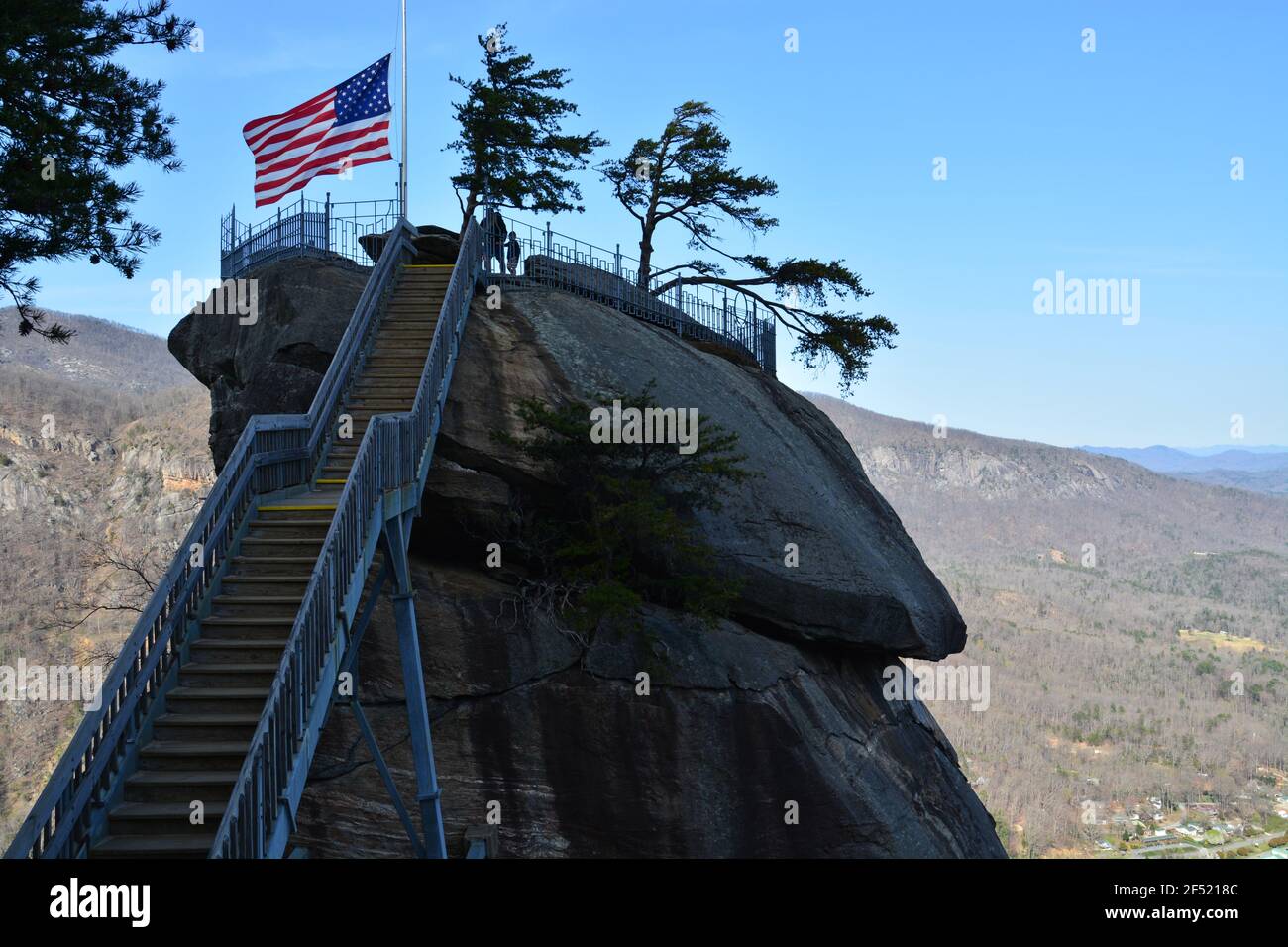 The American flag blows atop the namesake granite spire at Chimney Rock State Park outside of Asheville, North Carolina. Stock Photo