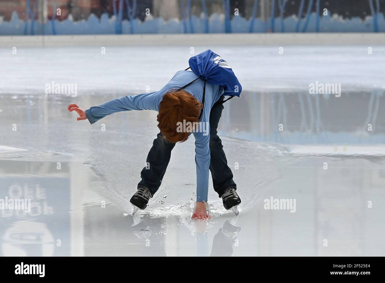 A young skater reaches down to run her hand through melted ice at the ...