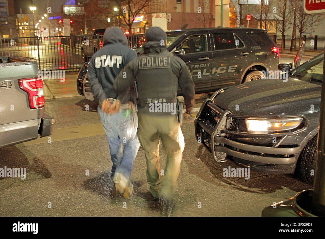 A Detroit police officer leads an arrested man away in handcuffs, Detroit, Michigan, USA Stock Photo