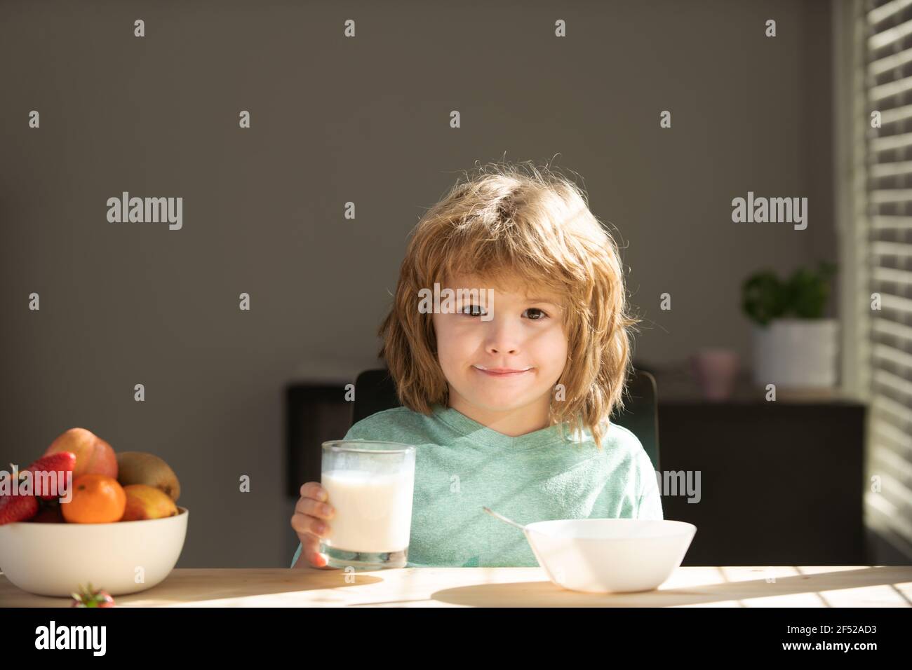 Cute child eating cereal with milk. Baby eating breakfast. Child eating healthy food. Stock Photo