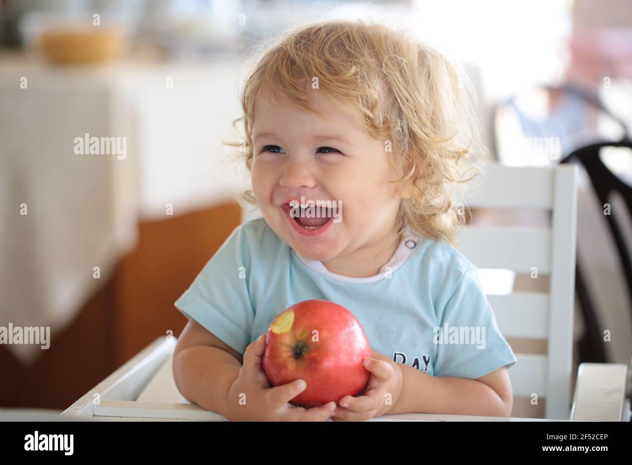 Laughing cute child eating apple. Cute baby eat apples. Portrait of