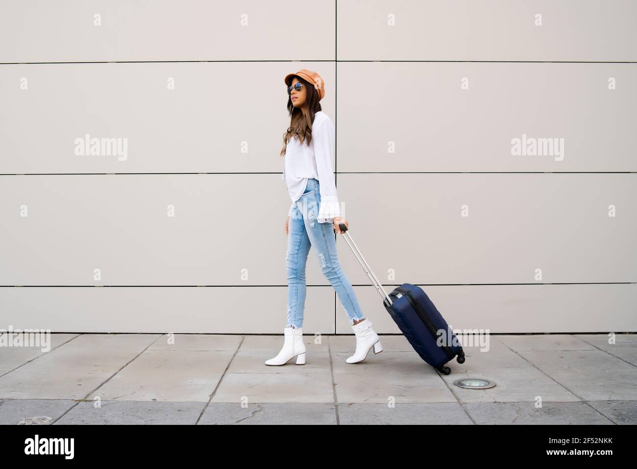 Young woman carrying a suitcase outdoors. Stock Photo