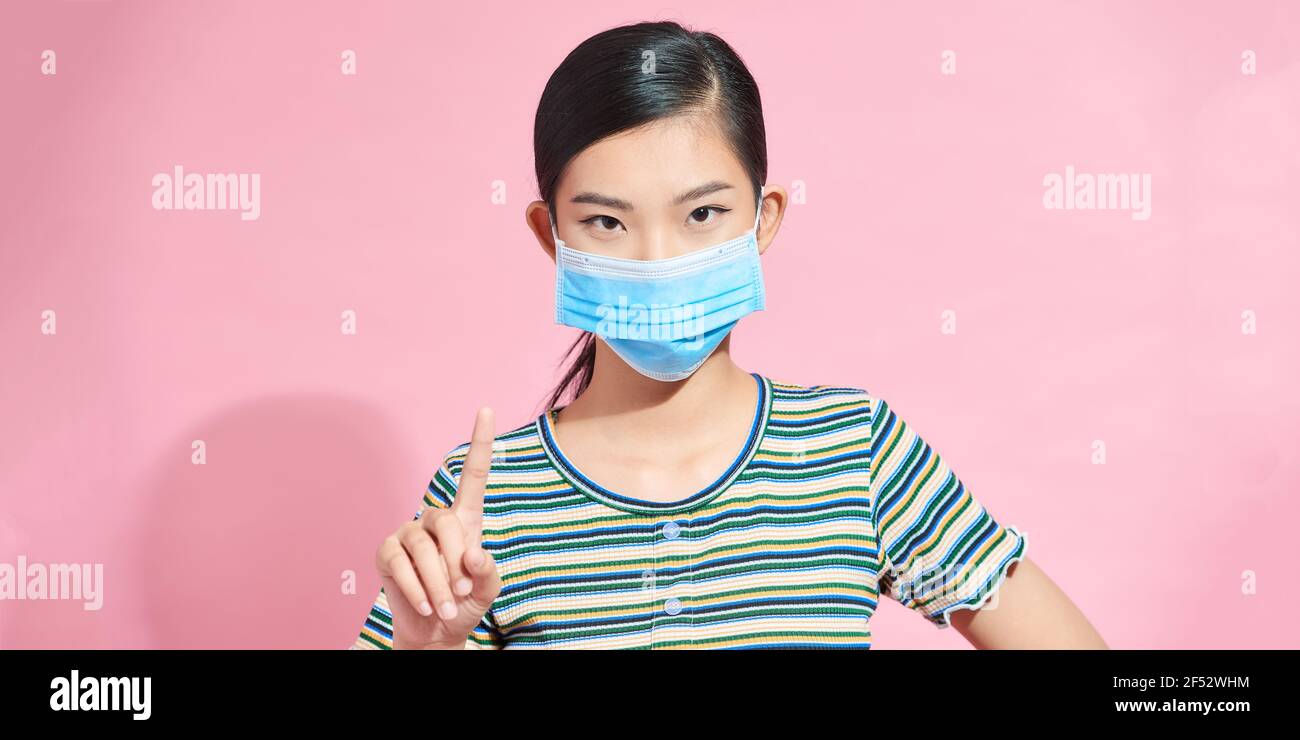 serious young woman in a medical protective mask on her face, standing ...