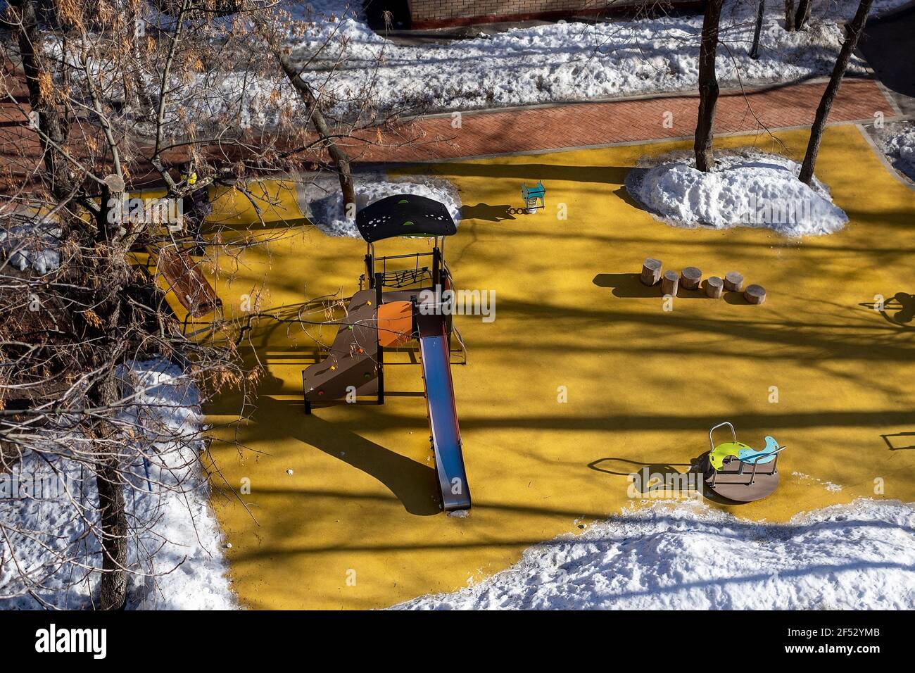 A children playground with a bunny hill in the center and melting snow