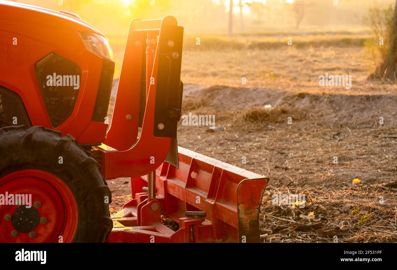 Orange tractor parked at rice farm in summer morning with sunlight