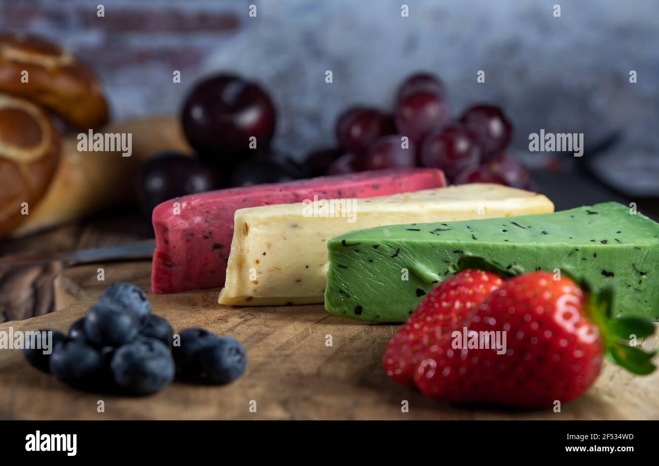 Top view of Different Dutch and Netherlands cheese types on plate and bread and fruit on wooden backdrop. Stock Photo