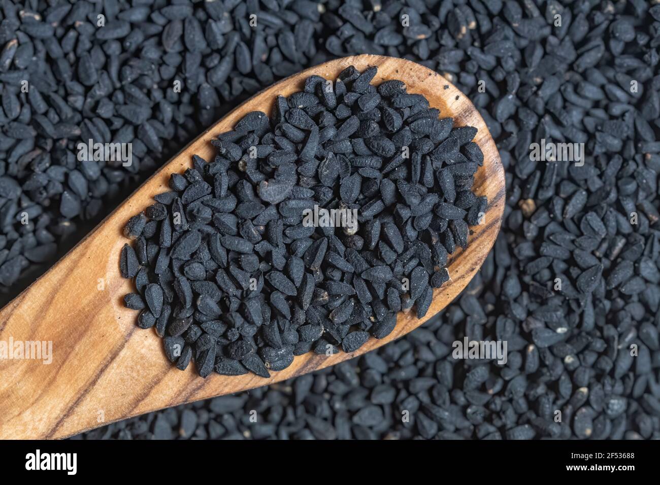 Nigella sativa seeds, close up photography, with a wooden spoon, selective focus. Stock Photo