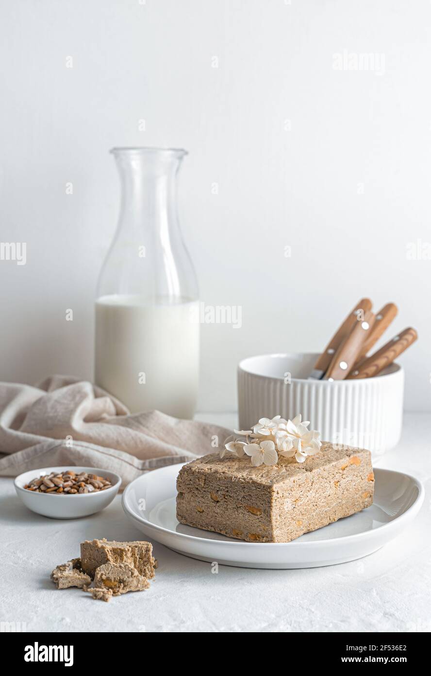 Halva with seeds and milk on a light background. Side view, vertical ...