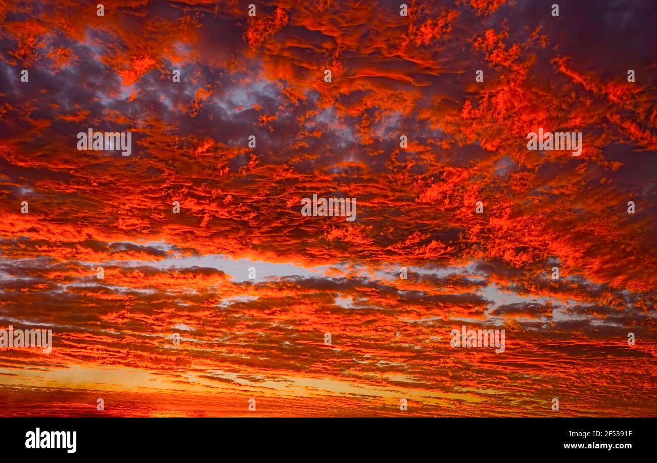 Stunning fiery red clouds at sunset in tropical North Queensland, Australia during monsoon season with vivid colors of reds and orange for background. Stock Photo
