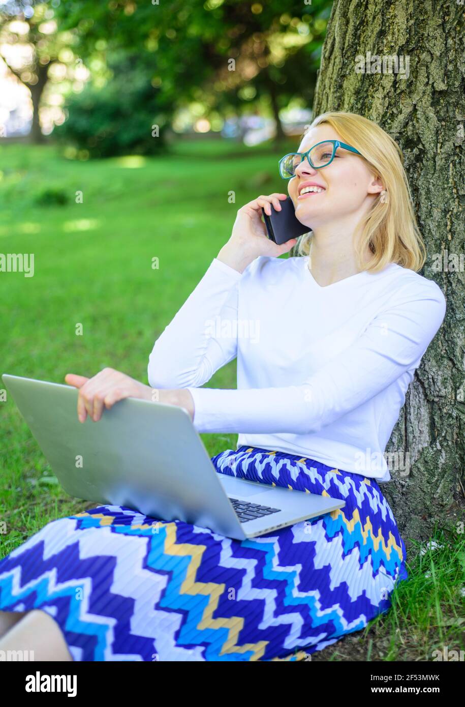 Girl sit grass with notebook. Woman with laptop in park order item on phone. Girl takes advantage of online shopping. Save your time with shopping Stock Photo