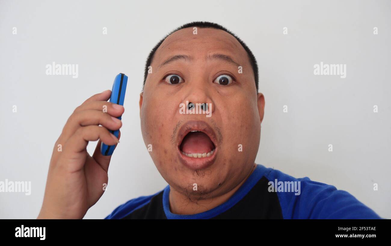 Asian man with bald hair is on the phone, with an old telephone with strange expression Stock Photo
