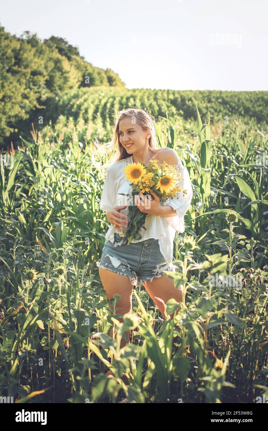 Downshifting, slow living, work life balance, wellness, wellbeing, healthy lifestyle. Young blonde women with wildflowers enjoying moment in nature Stock Photo