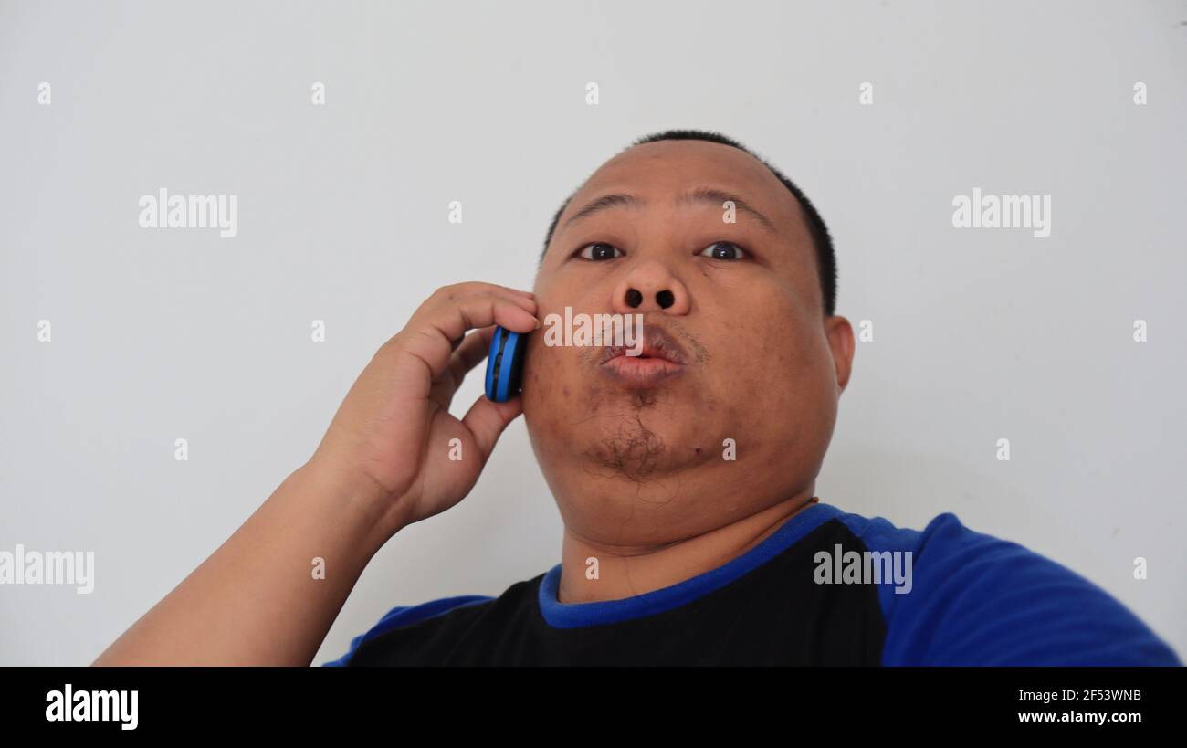 Asian man with bald hair is on the phone, with an old telephone with strange expression Stock Photo