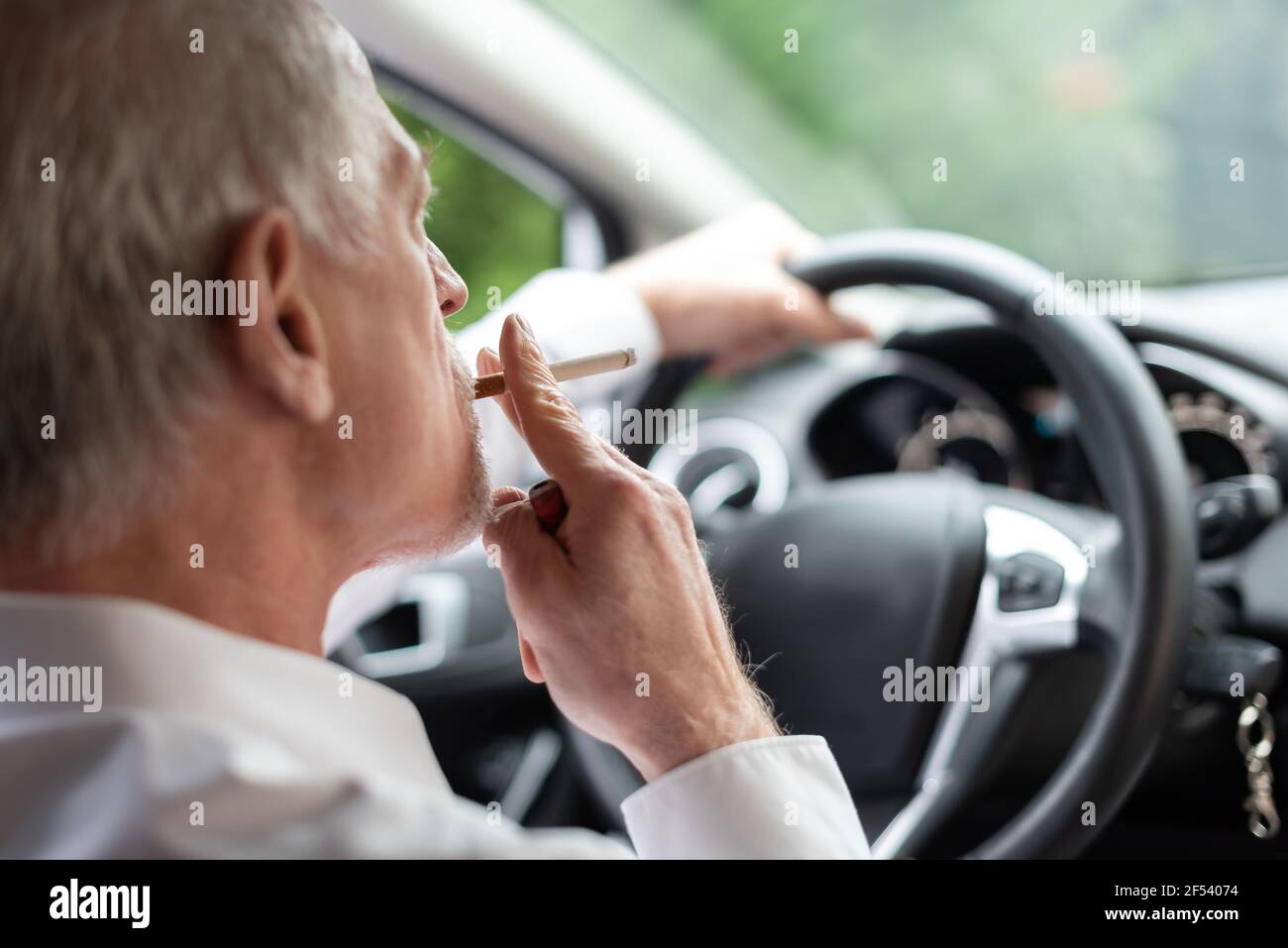 Senior man smoking a cigarette while driving Stock Photo