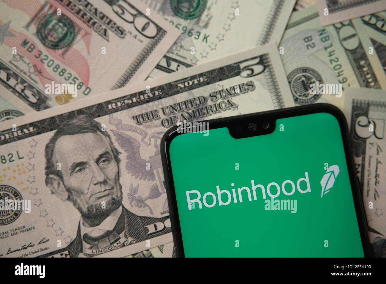 Robinhood app logo seen on smartphone on US dollar banknotes. Robinhood is an investing and trading app for shares, stocks and crypto currency. Staffo Stock Photo