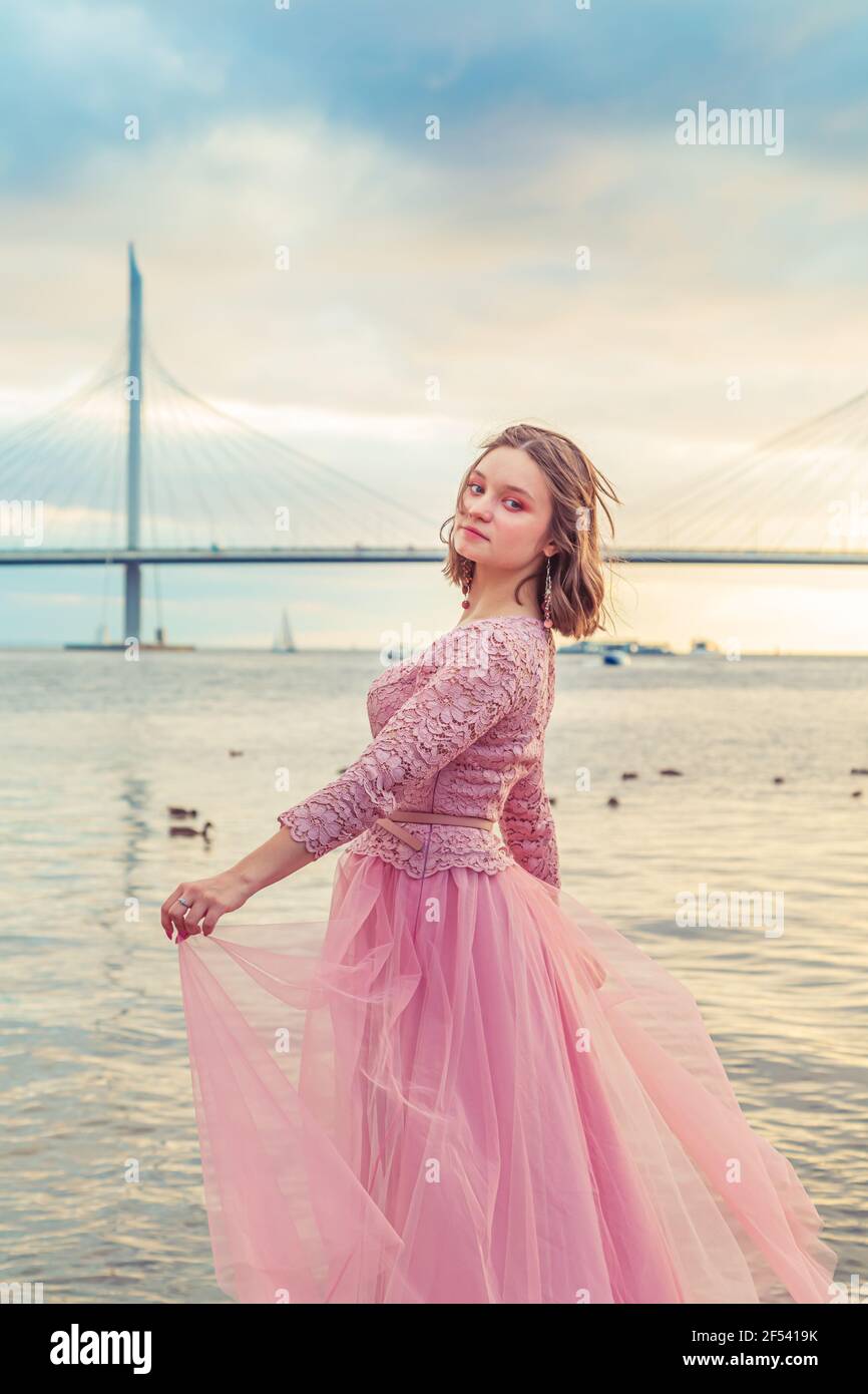 Young girl in a pink dress is dancing on the seashore. Carefree ...