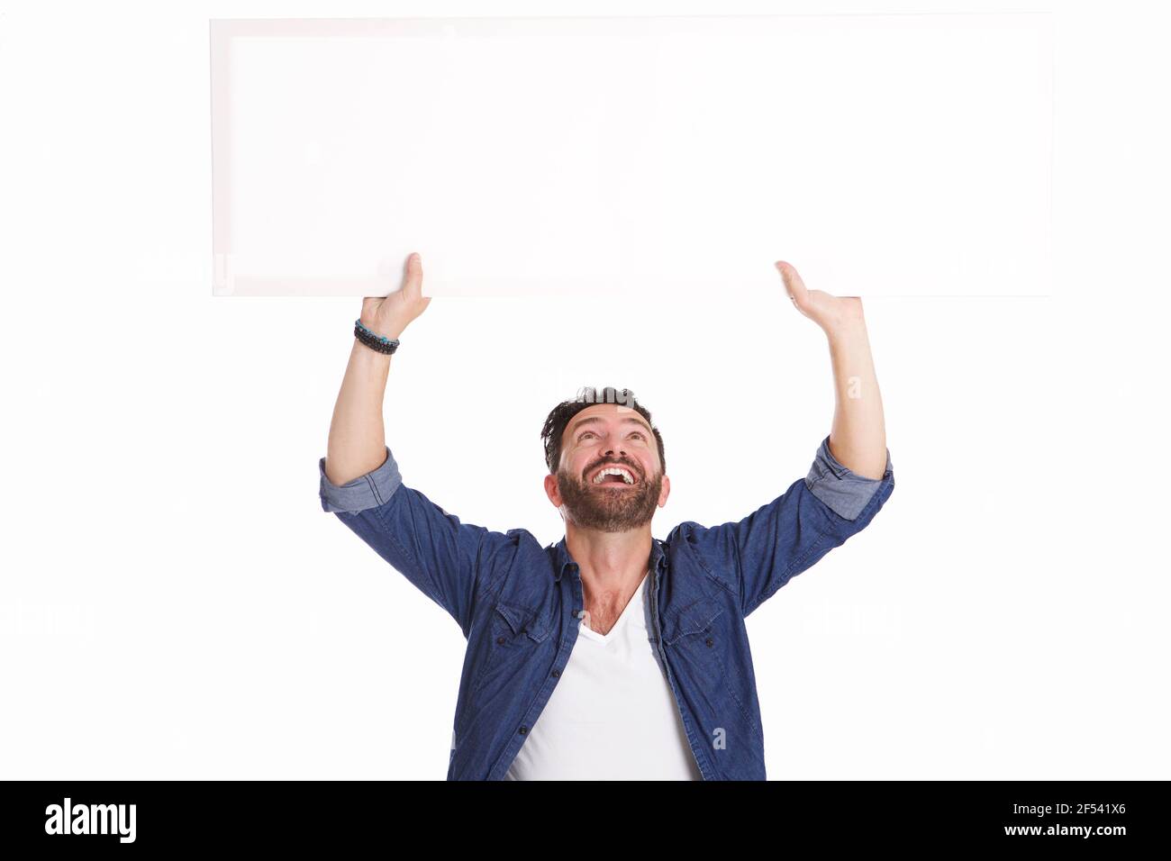 Portrait of mature man laughing and holding blank poster sign on white background Stock Photo