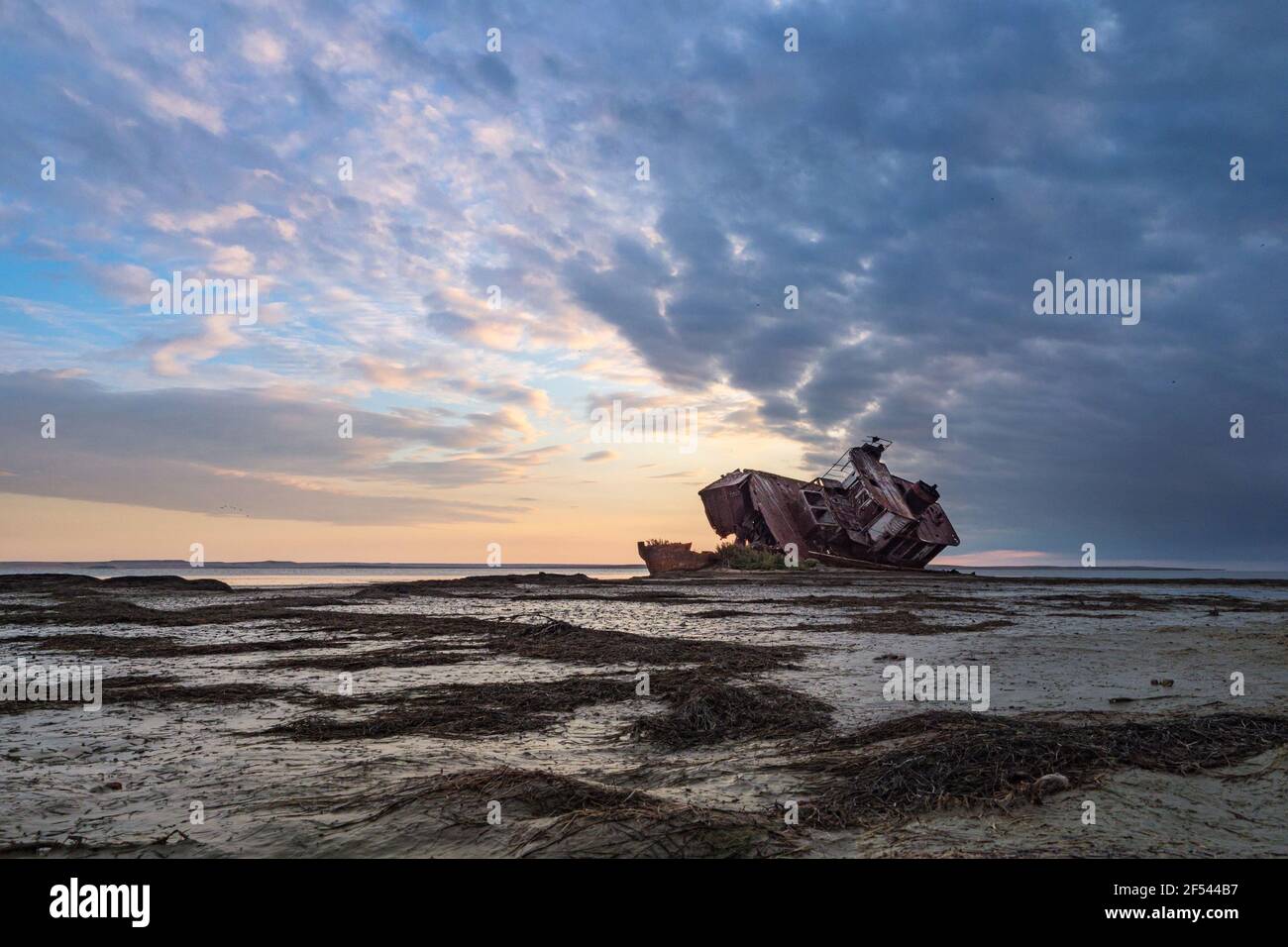 An old abandoned ship on the shore of the drying up Aral Sea. Kazakhstan. Abandoned ships sawn for scrap by local residents. Ecological disaster of th Stock Photo